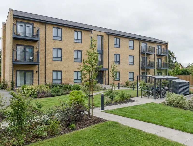 New three-storey low-rise apartment block with balconies and a communal garden