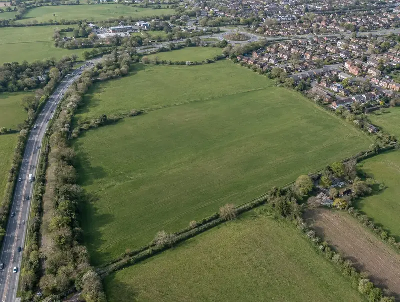 Aerial view of open farmland with hedgerows on the edge of a town